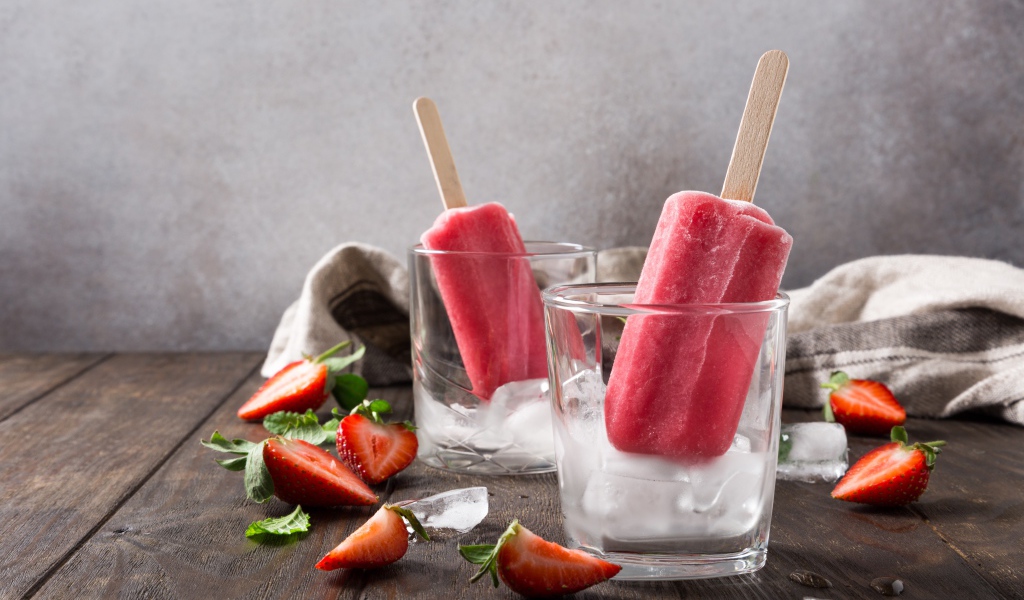 Фруктовое мороженое в стакане со льдом на столе с клубникой