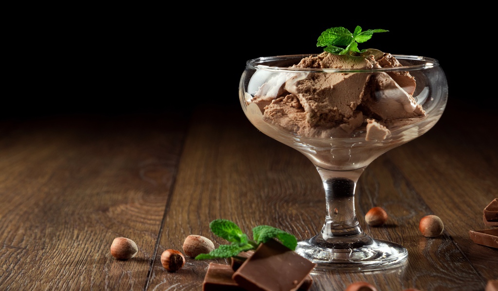 Кофейное мороженое в креманке на столе с шоколадом и орехами