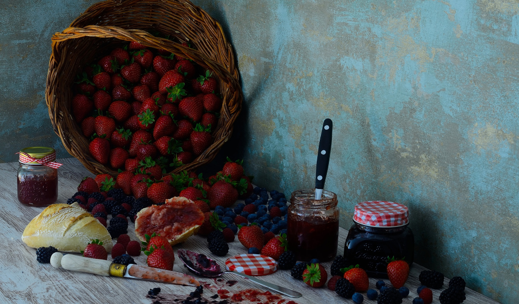 Jam on a table with berries and a loaf
