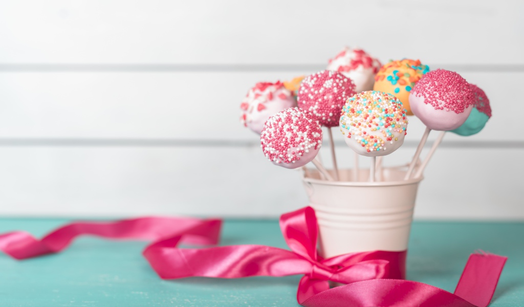 Леденцы в стакане на столе с розовым бантом из ленты