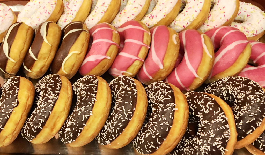 Много вкусных сладких пончиков с глазурью на столе 