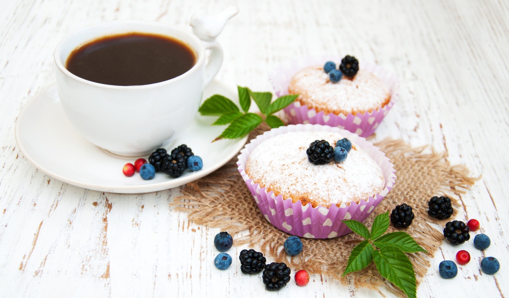 Кексы с сахарной пудрой и ягодами на столе с какао