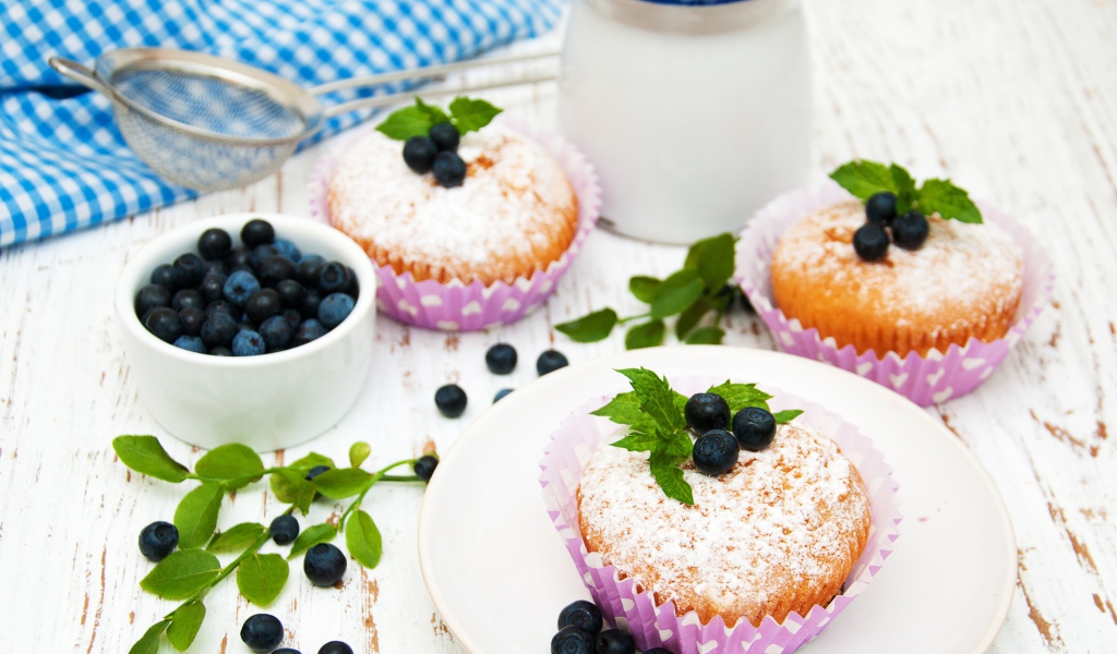 Кексы с сахарной пудрой на столе с молоком и черникой