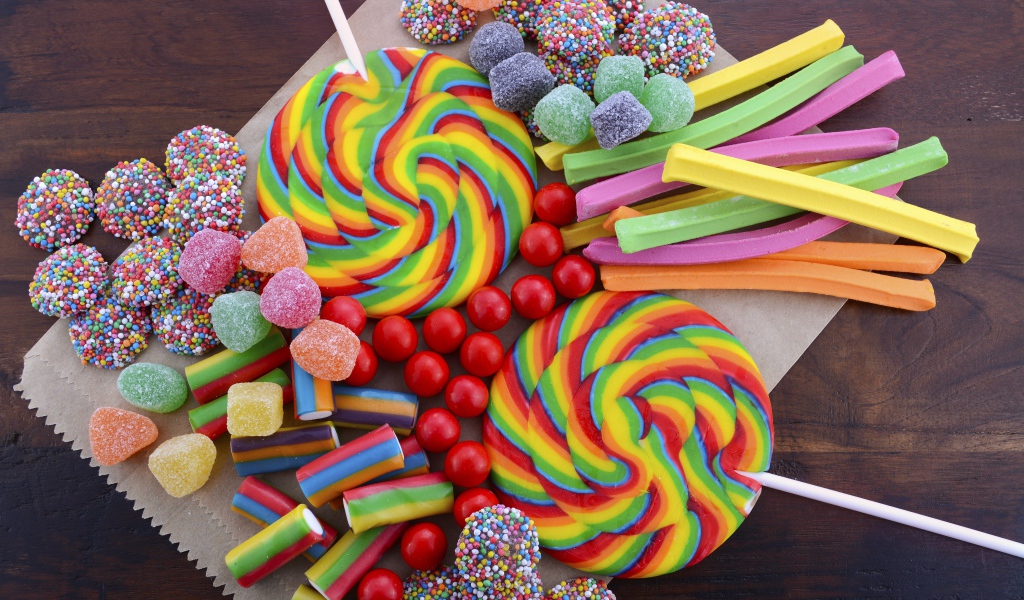 Разноцветные желейные конфеты, мармелад и леденцы на палочке на столе