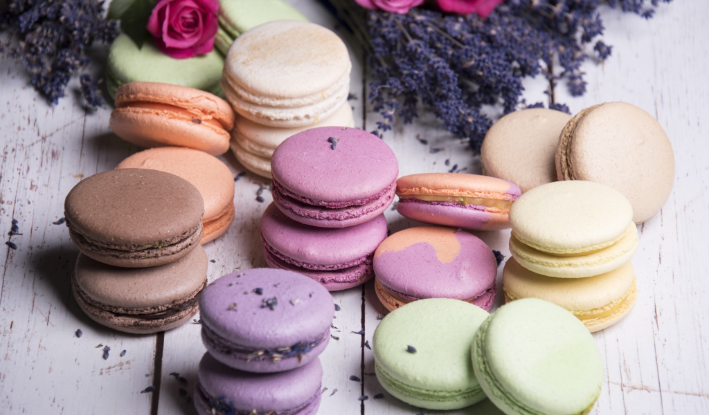 Разноцветный десерт макарон на столе с лавандой и розами