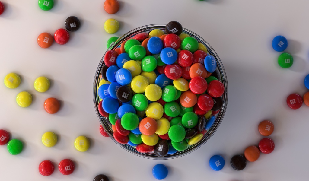 Разноцветные конфеты с миске на сером столе