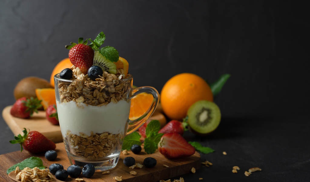 Овсяные хлопья с чашке с йогуртом на столе с ягодами и фруктами