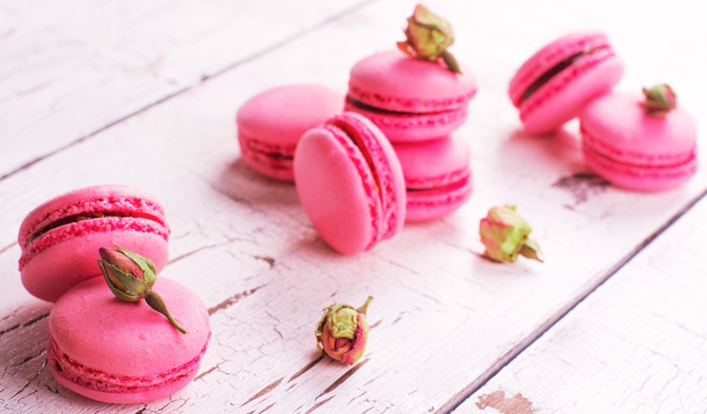 Розовый десерт макарон на столе с сухими розами