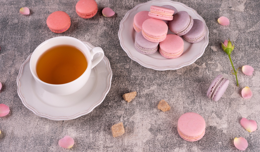 Тарелка с десертом макарун на столе с чашкой чая