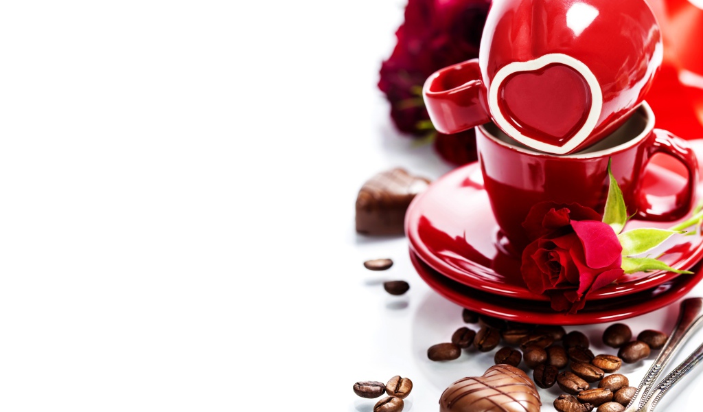 Красные чашки на белом фоне с шоколадными конфетами и кофейными зернами