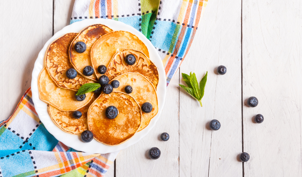 Румяные оладьи на тарелке с ягодами черники
