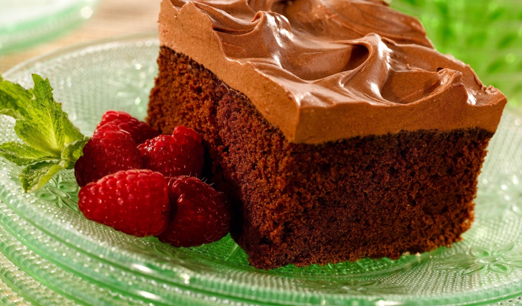 Бисквит с кремом и свежей малиной на тарелке