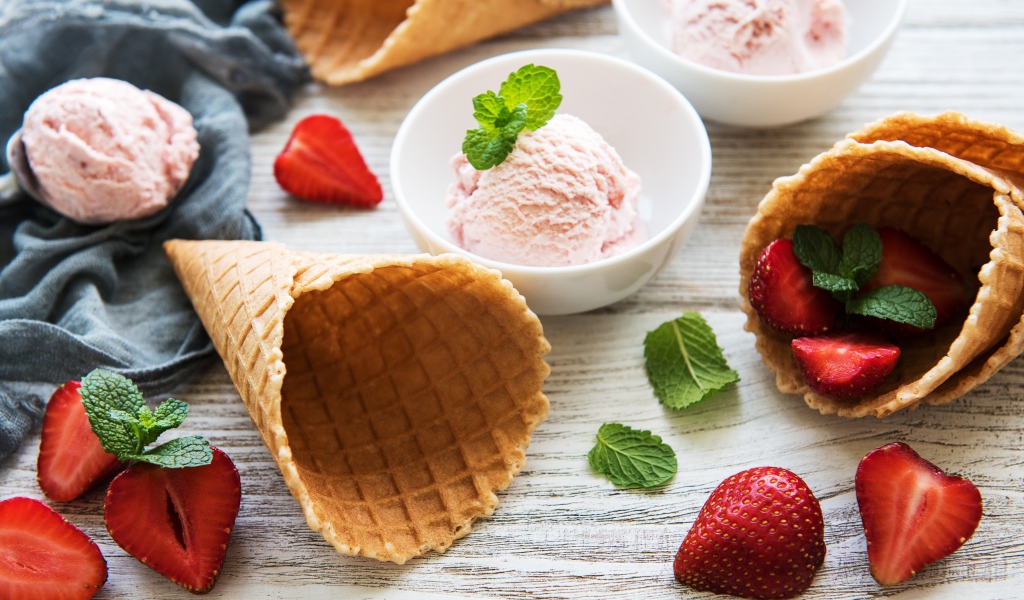 Клубничное мороженое на столе с рожками и клубникой