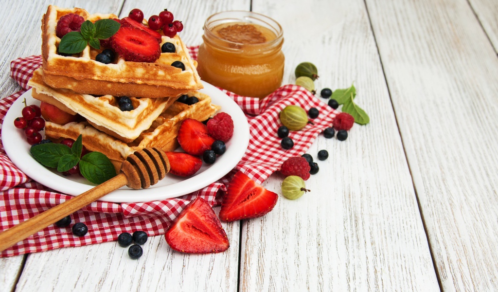 Сладкие вафли на столе с ягодами и медом