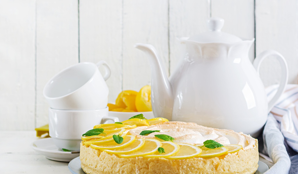 Вкусный песочный пирог с лимоном на столе с чашками и чайником