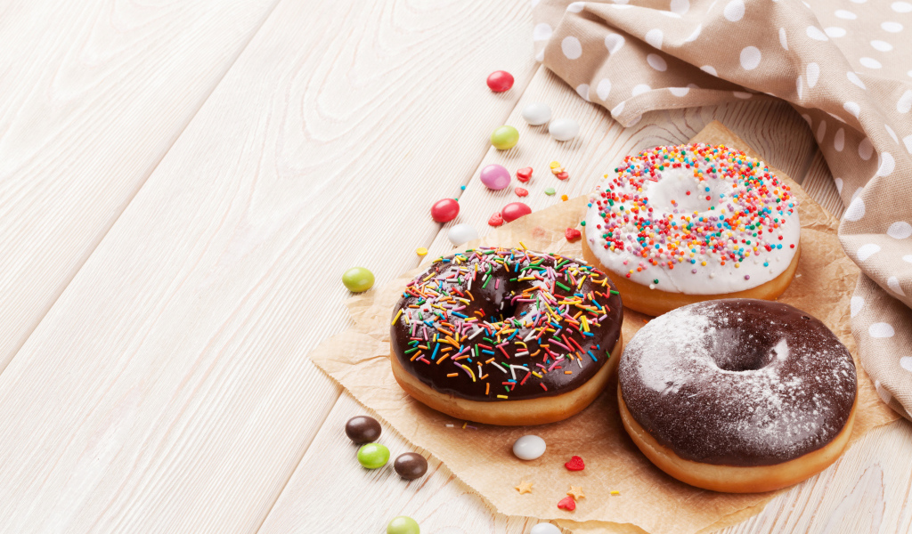 Три аппетитных пончика с глазурью на столе 