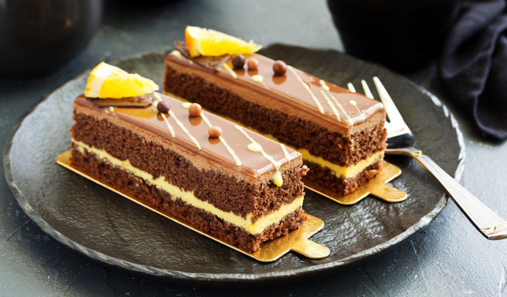 Два вкусных шоколадных пирожный на большой тарелке с вилкой