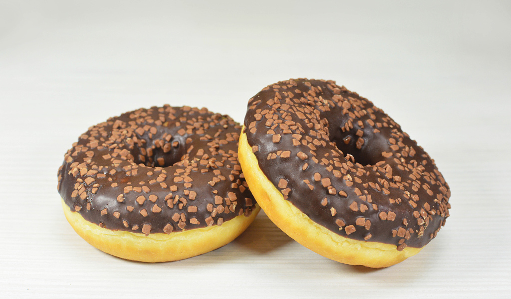 Два сладких пончика с шоколадом на сером фоне
