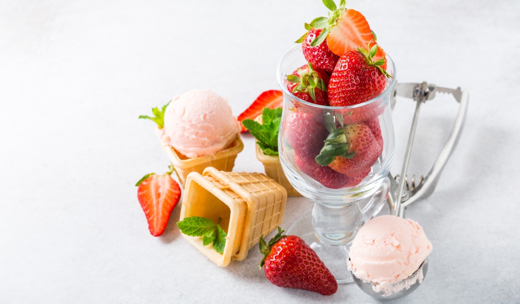 Вафельные стаканчики с мороженым на столе со свежей клубникой