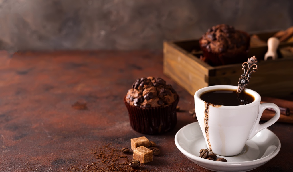 Белая чашка кофе и кекс с шоколадом на столе