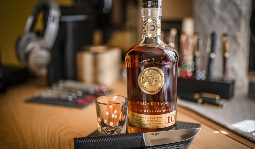 Бутылка виски на столе с рюмкой и ножом