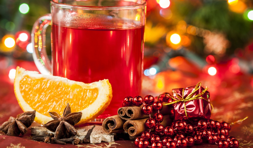 Чашка горячего чая на столе с корицей, бадьяном и кусочком апельсина 