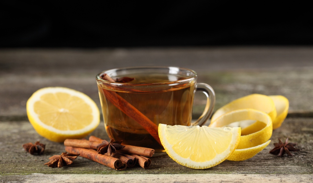 Чашка чая на столе с корицей и кусочками лимона 