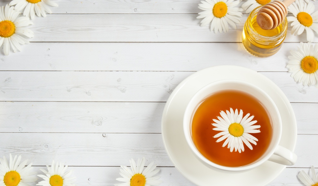 A cup of tea with chamomile on the table with honey