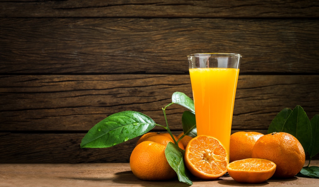 Стакан апельсинового сока на столе с мандаринами