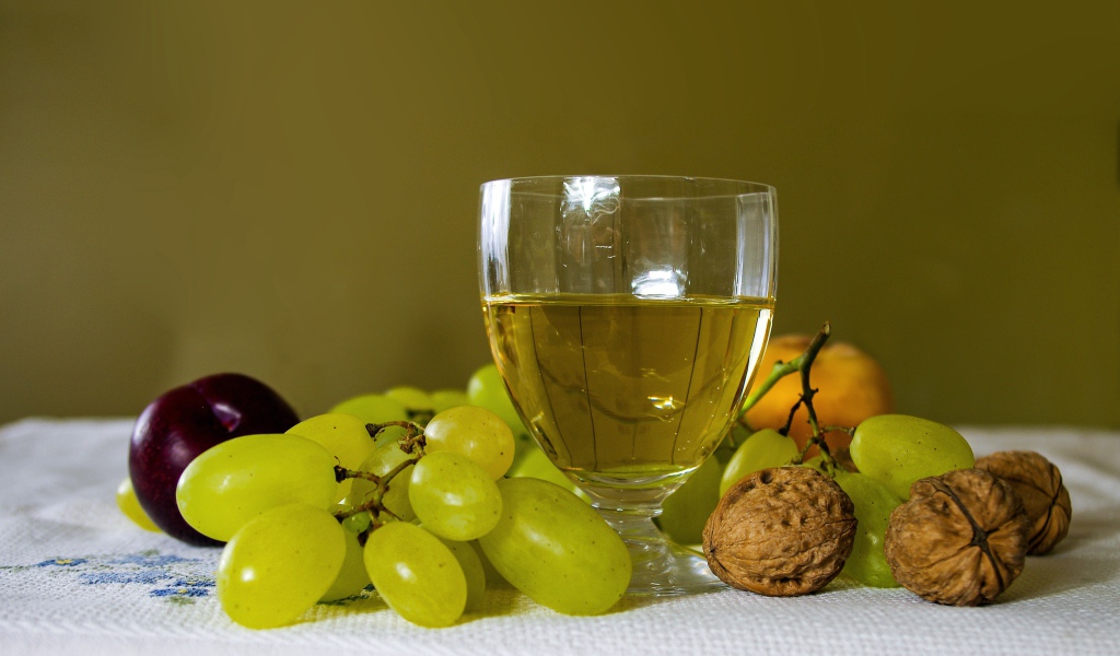 Бокал белого вина на столе с виноградом и орехами
