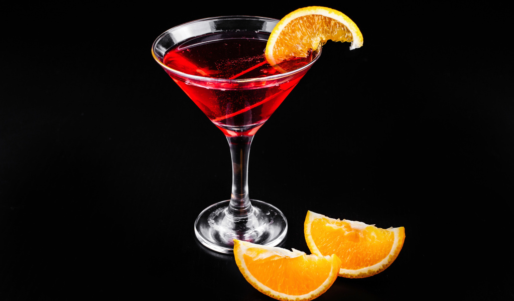Алкогольный коктейль с кусочками апельсина на черном фоне