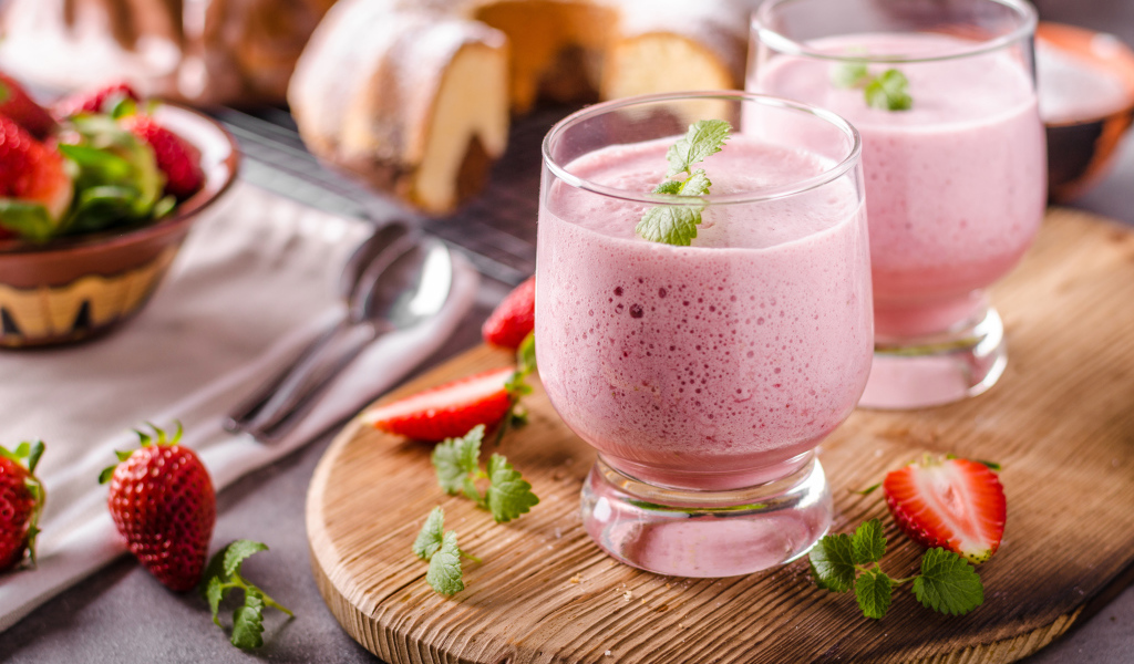 Ягодное смузи в стаканах на столе с клубникой