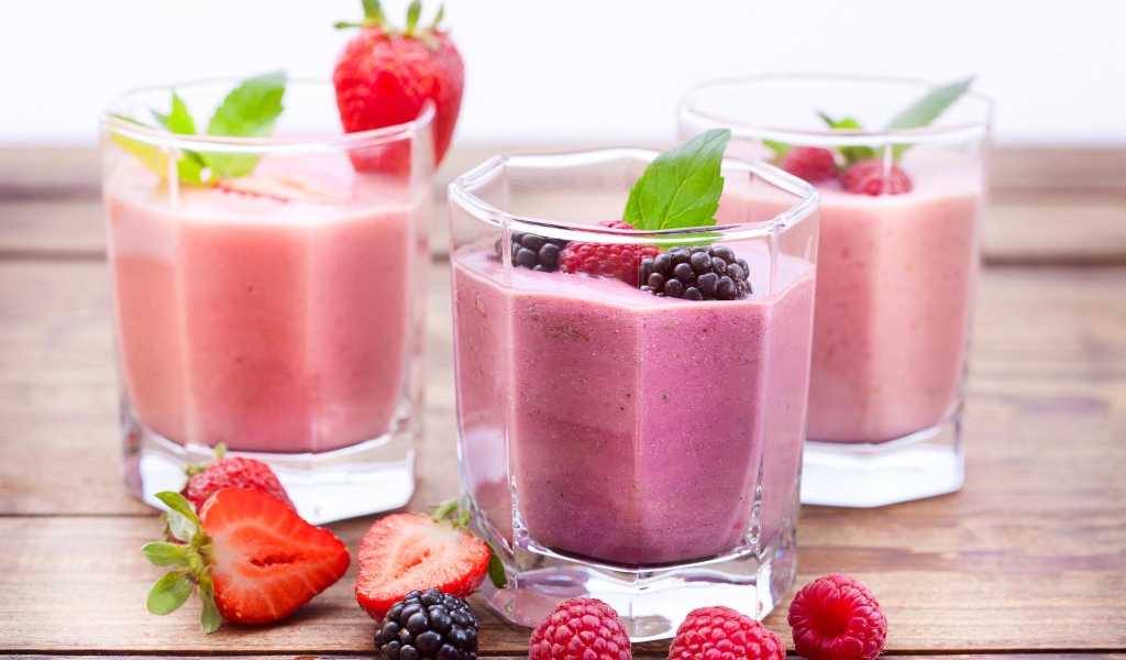 Ягодное смузи в стаканах на столе с ягодами малины, черники и клубники
