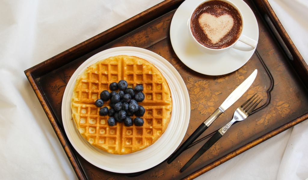 Капучино в чашке на подносе с вафлями и черникой 