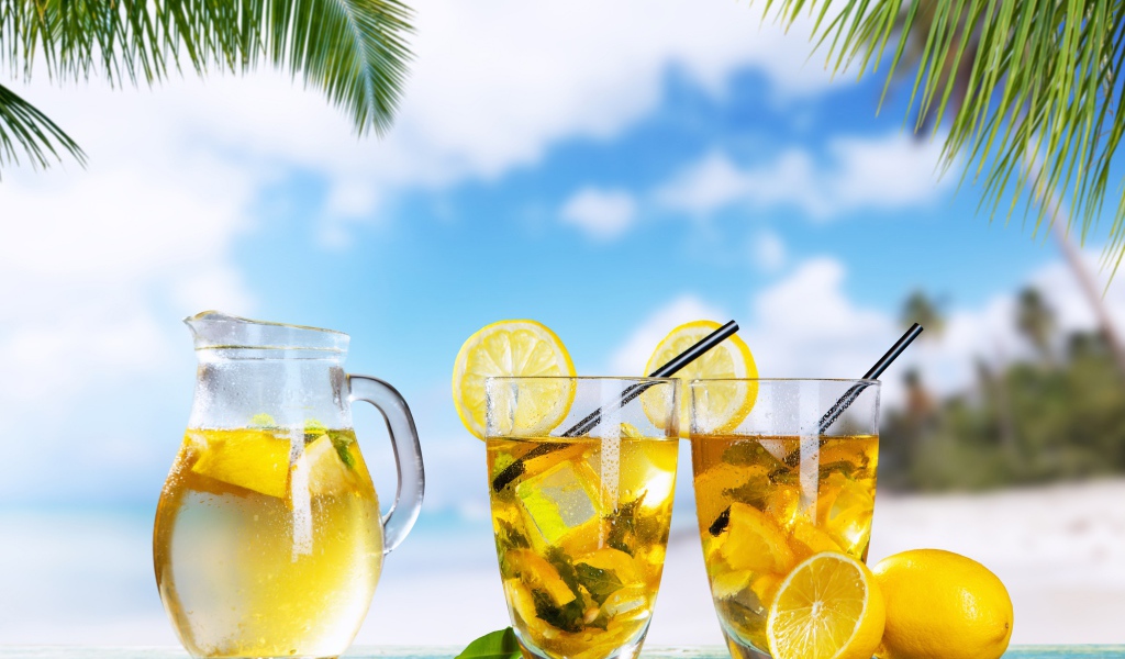 Графин и два стакана лимонада на столе на тропическом пляже