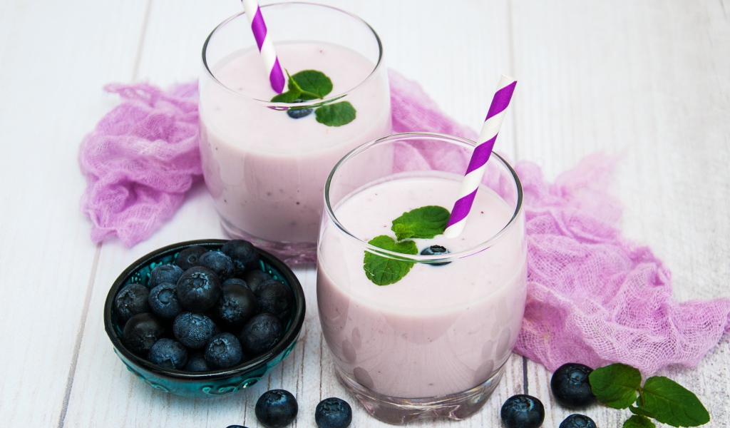 Коктейль в стаканах на столе с ягодами черники