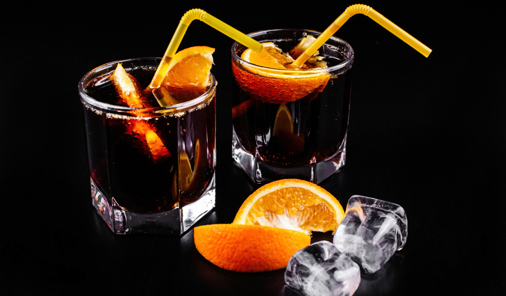 Коктейль с кусочками апельсина на черном фоне со льдом
