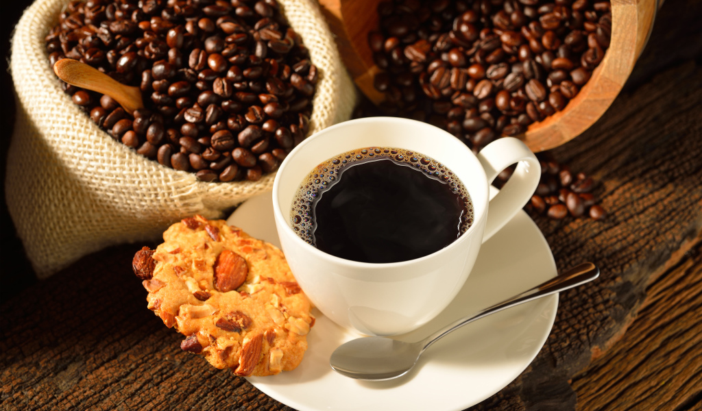 Кофейные зерна на столе с белой чашкой и печеньем