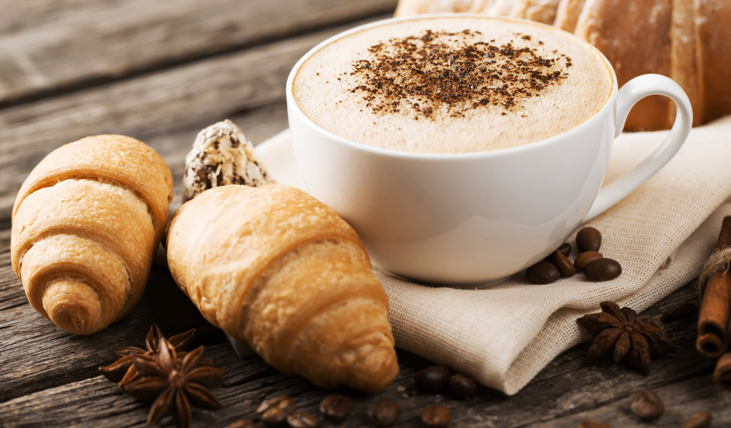 Чашка капучино на столе круассанами