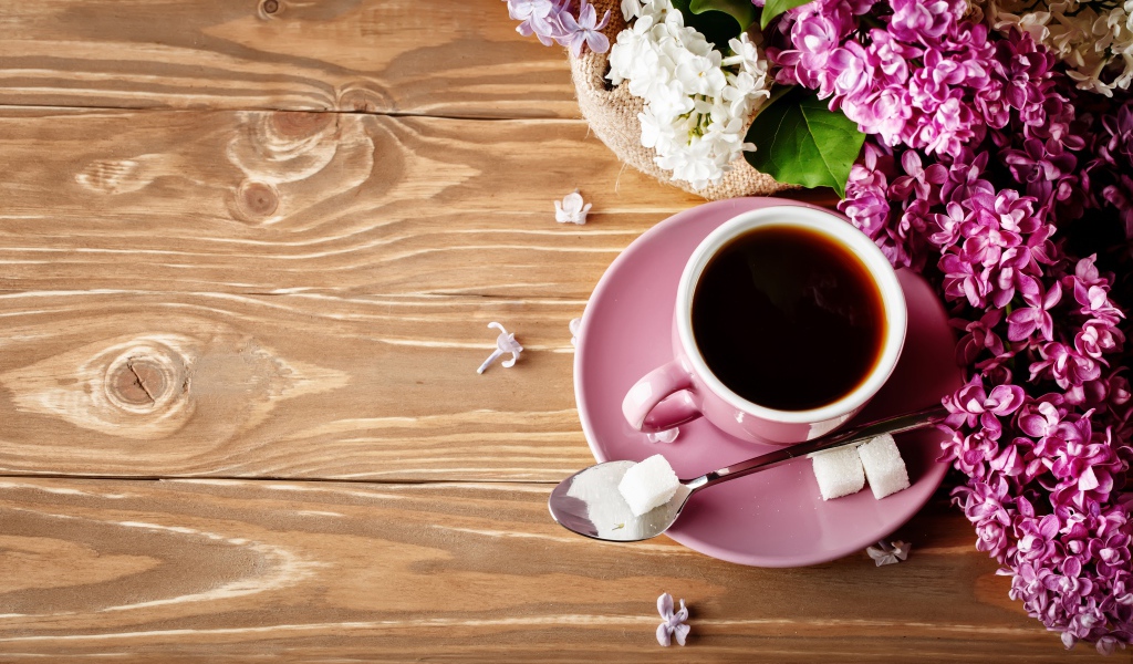 Чашка кофе на деревянном столе с сиренью 