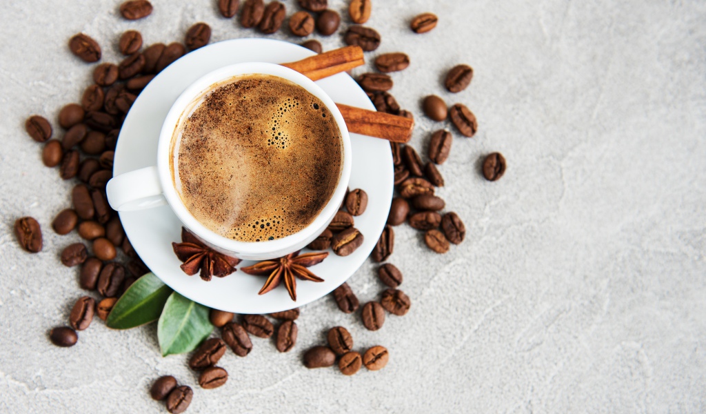 Чашка кофе с кофейными зернами на столе с корицей и бадьяном