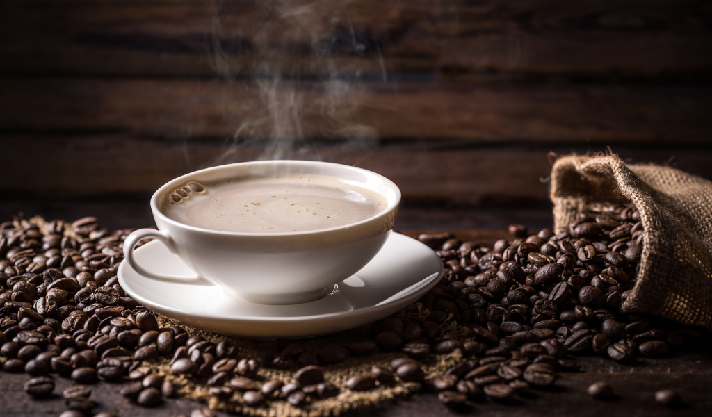 Чашка горячего ароматного кофе на столе с зернами