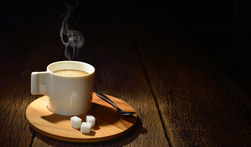 Чашка горячего кофе на столе с сахаром