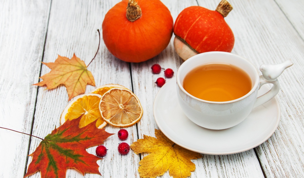 Чашка чая на столе с опавшими листьями и тыквой