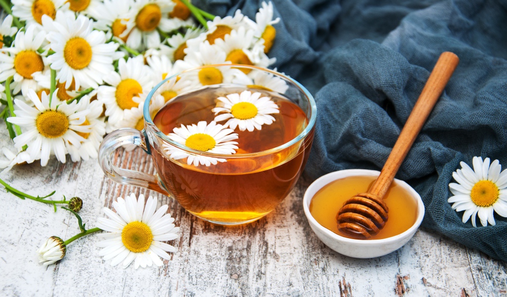 Чашка чая на столе с медом и букетом ромашек
