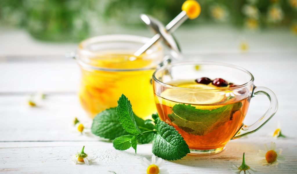 Чашка чая с лимоном и мятой на столе с медом