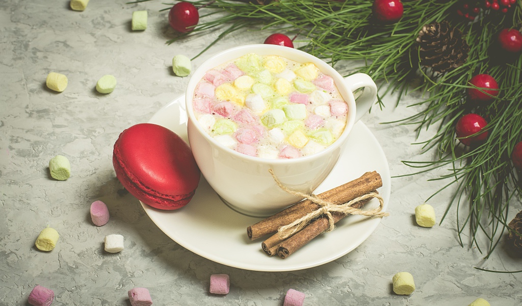 Напиток с маршмелоу на блюдце с макаруном и корицей