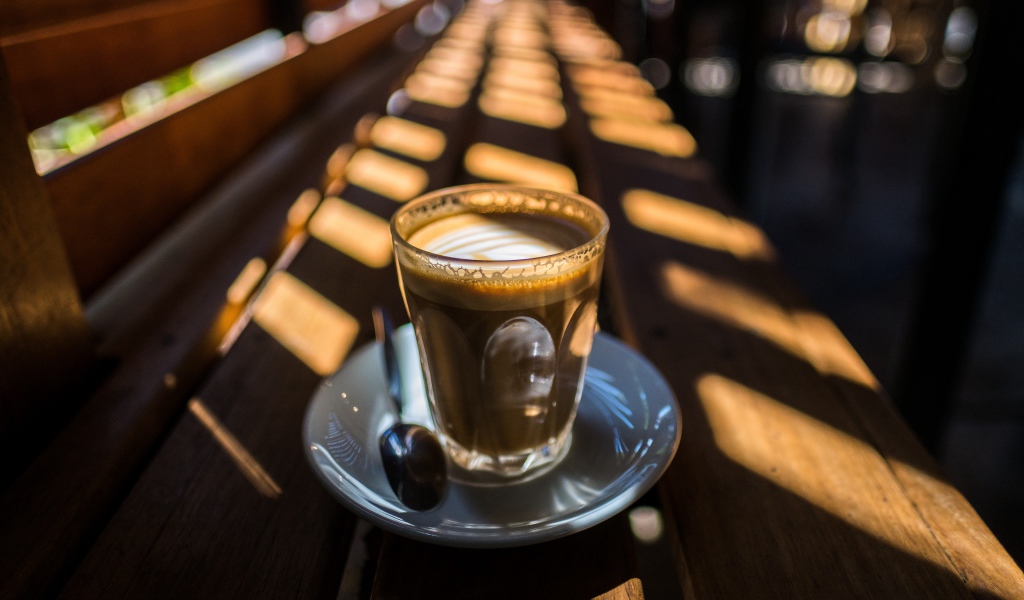 Стакан с кофе стоит на деревянном лавке