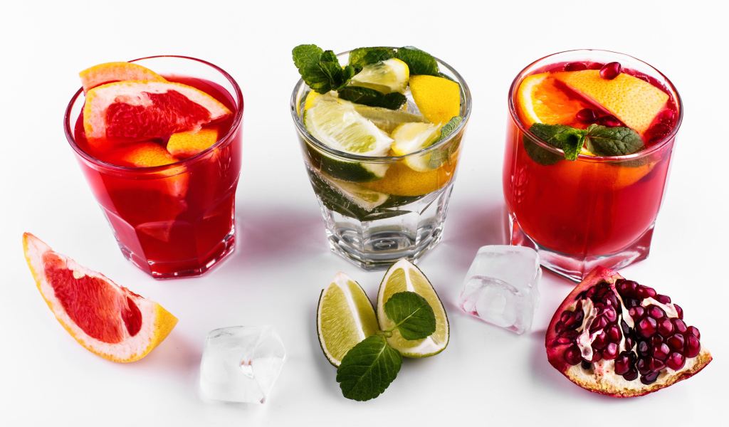 Стаканы с цитрусовыми коктейлями со льдом на белом фоне с фруктами