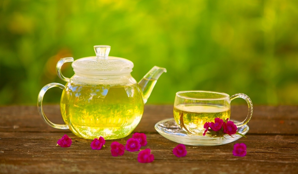 Зеленый чай на столе в стеклянном чайнике и чашке